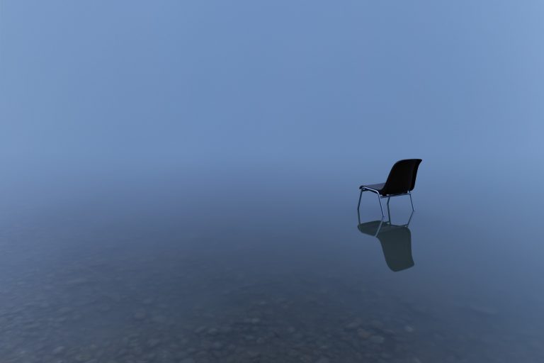 A single chair reflecting on a water surface on a stormy day